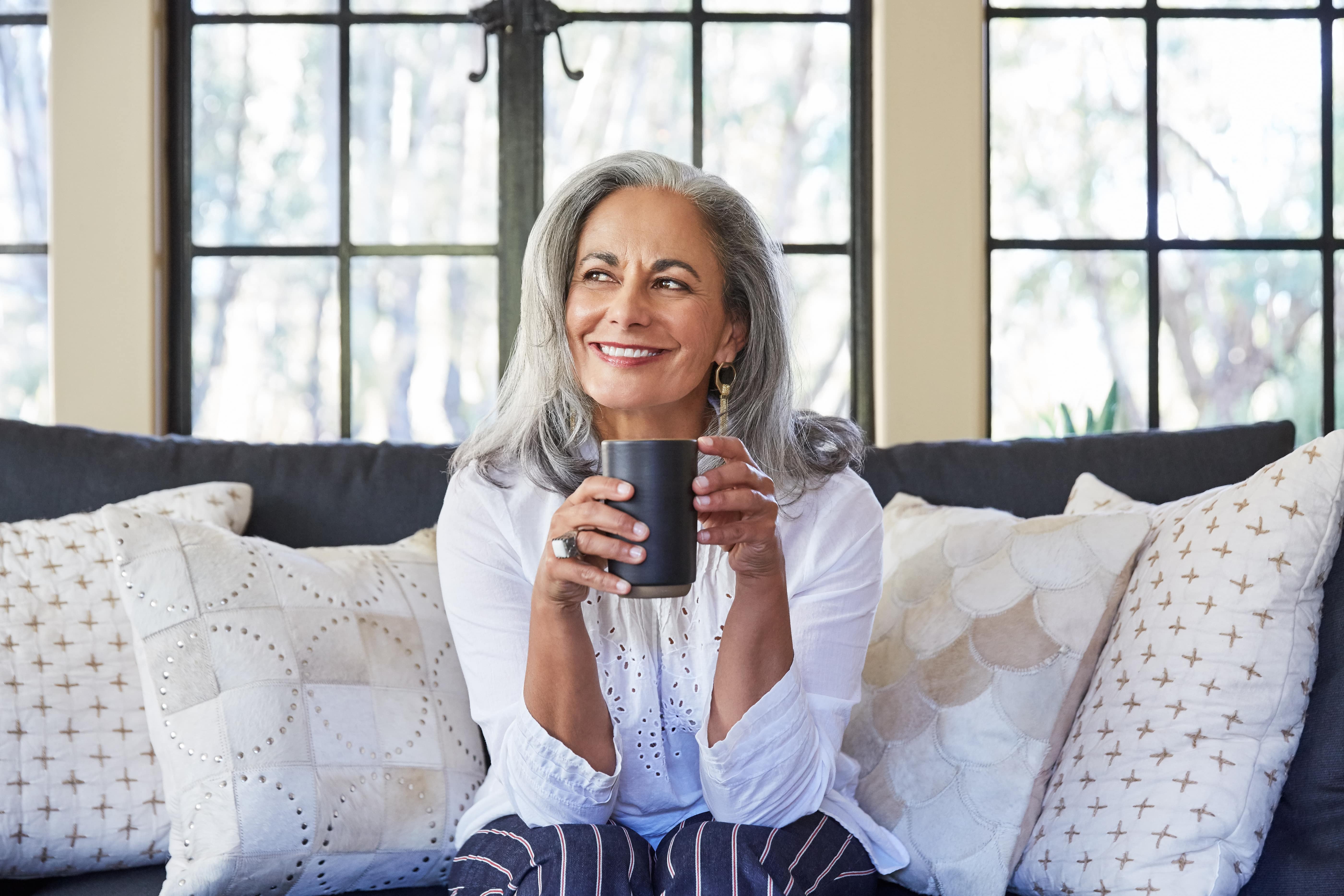 Older woman sitting on a couch holding coffee