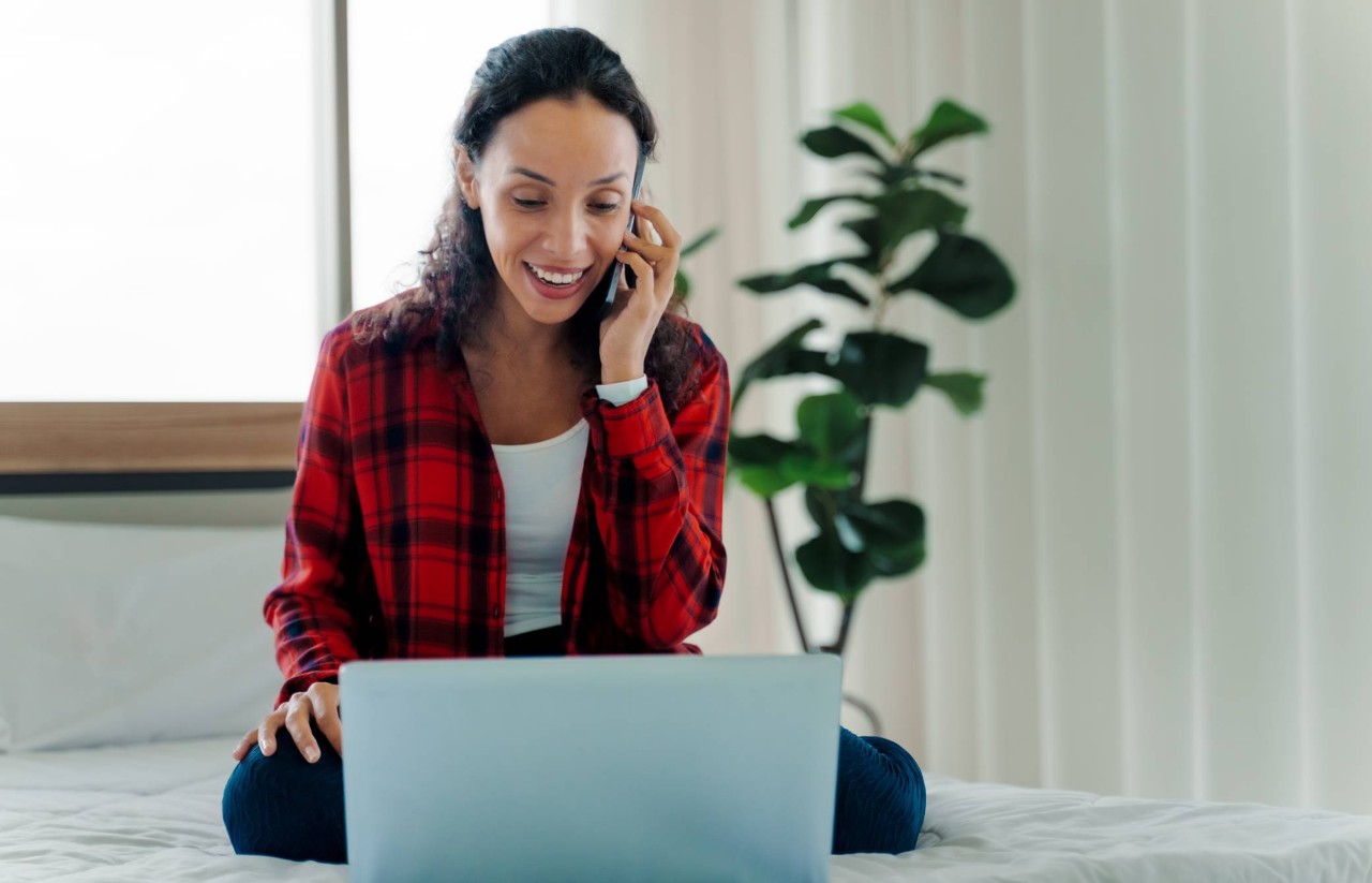 Woman sitting behind a laptop while speaking on the phone