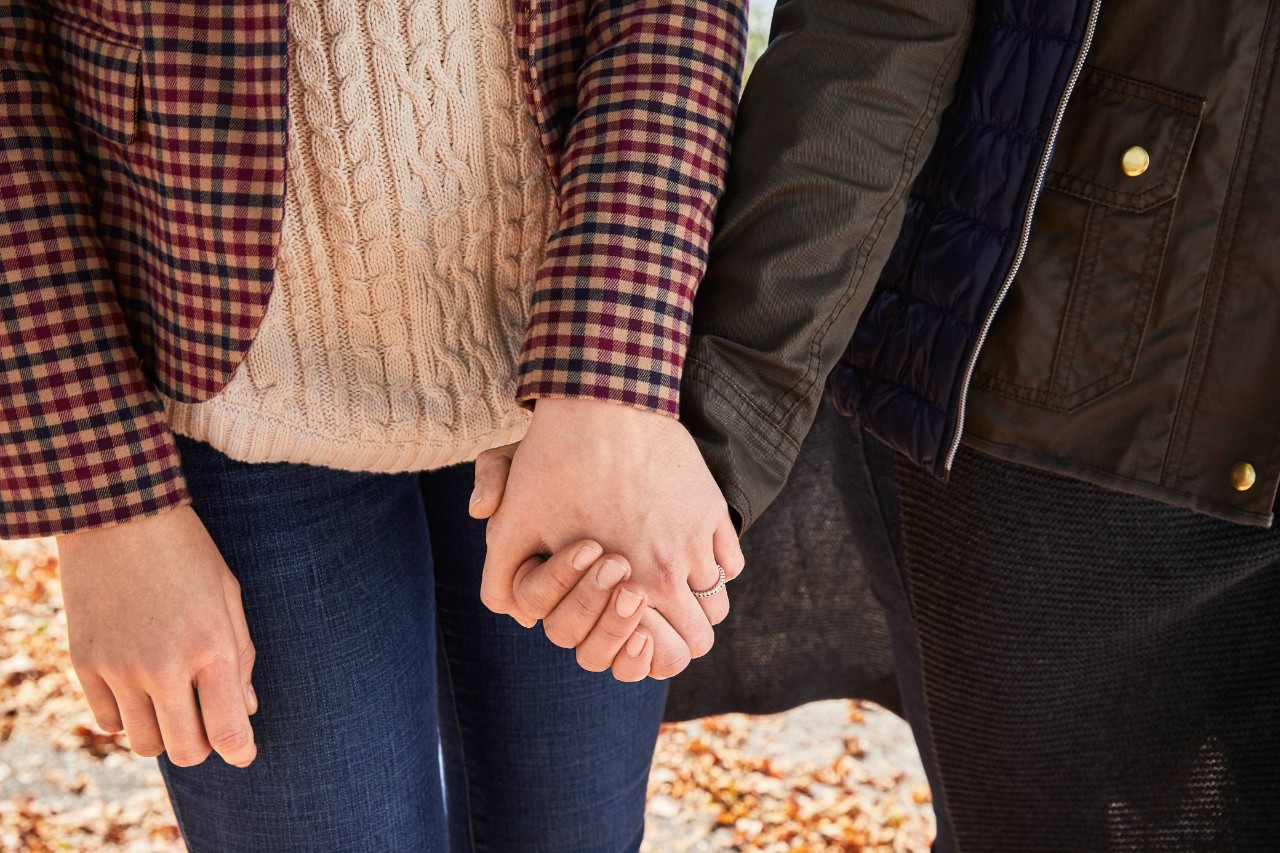 Up-close shot of two people holding hands.