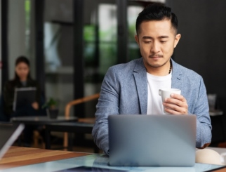 man on computer with coffee in hand