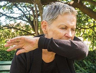 Woman outside, sneezing into her sleeve