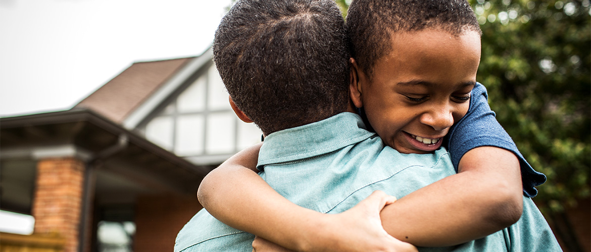 Man holds child as he stands outside a house
