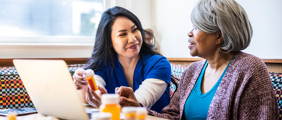 female nurse explains prescription pill bottle directions to female patient