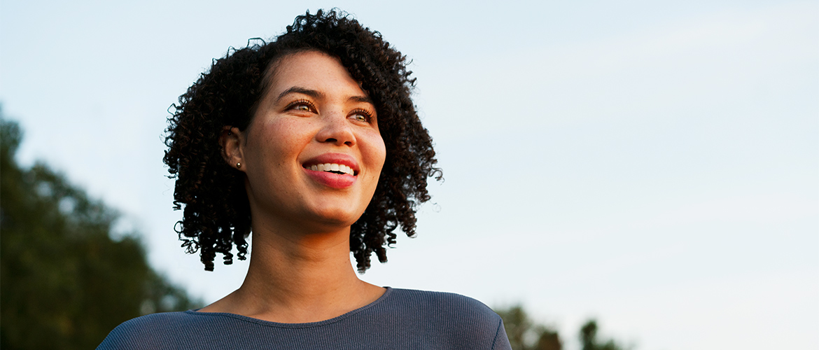 woman with black curly hair looks into the sky