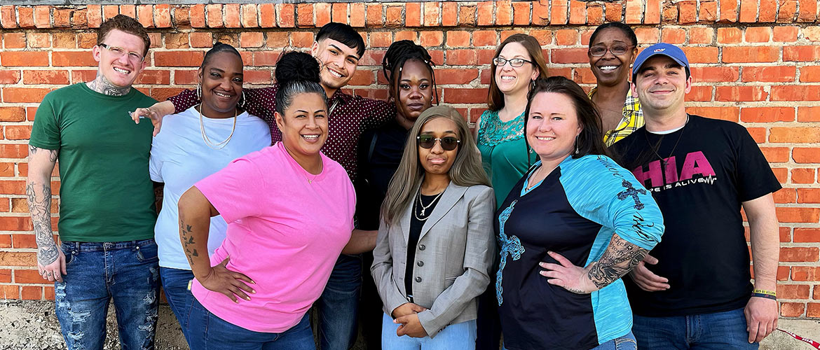 ten men and women smiling in front of a brick wall