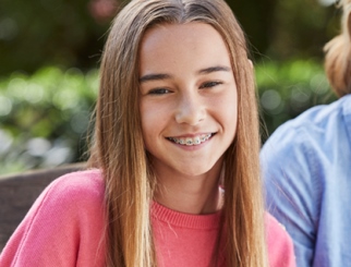 Adolescente con frenos sonriéndole a la cámara.