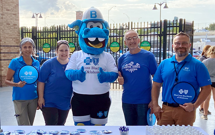 Especialistas en Compromiso con la comunidad en un evento con la mascota de BCBSOK, Blaze the Braggin' Blue Dragon.