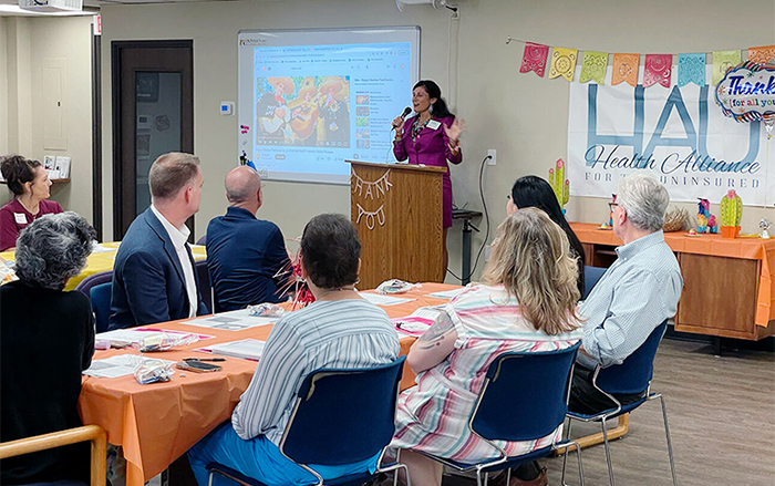 Woman at podium presents to room of adults