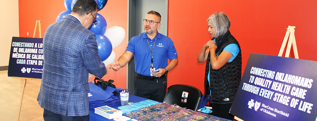 Two employees chat with community member at tabling event