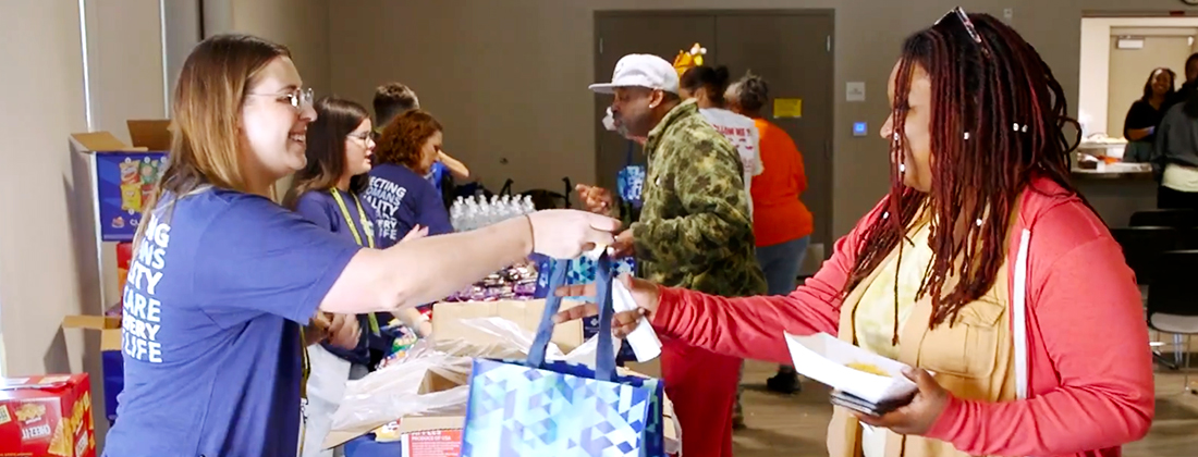 Una voluntaria entrega un paquete de donativos a un miembro de la comunidad