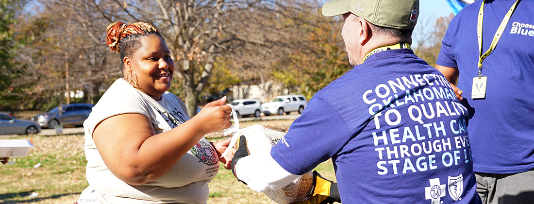 BCBSOK volunteer gives turkey to community member