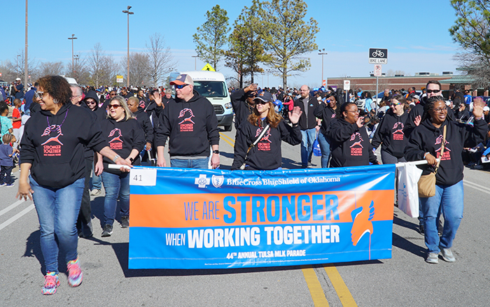 ​​​​​​​Empleados de BCBSOK sostienen una bandera y participan en el desfile MLK