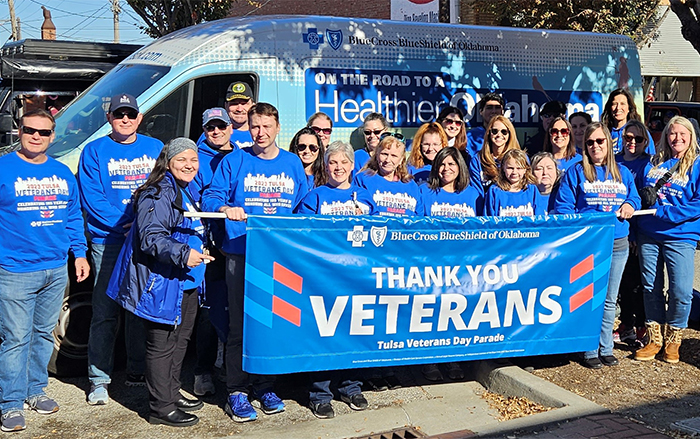 Employees pose in front of Care Van® with "Thank you Veterans" banner