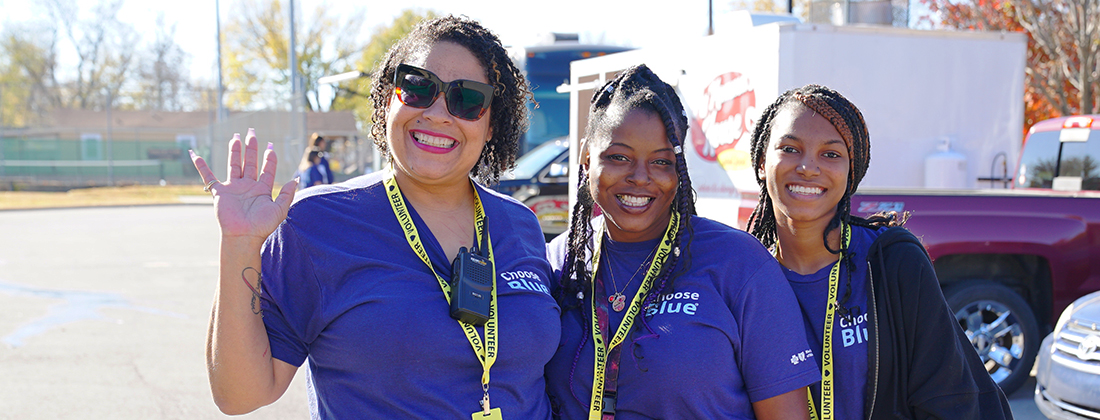 Three employees pose together smiling