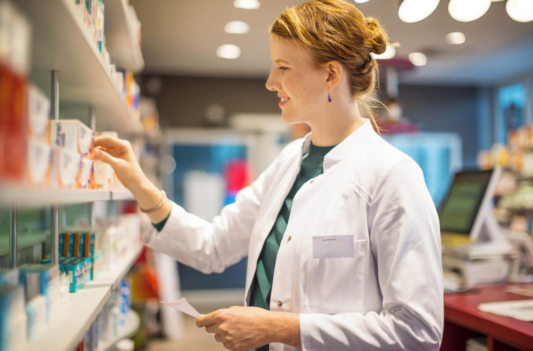 Farmacéutico buscando un medicamento con receta y sonriendo