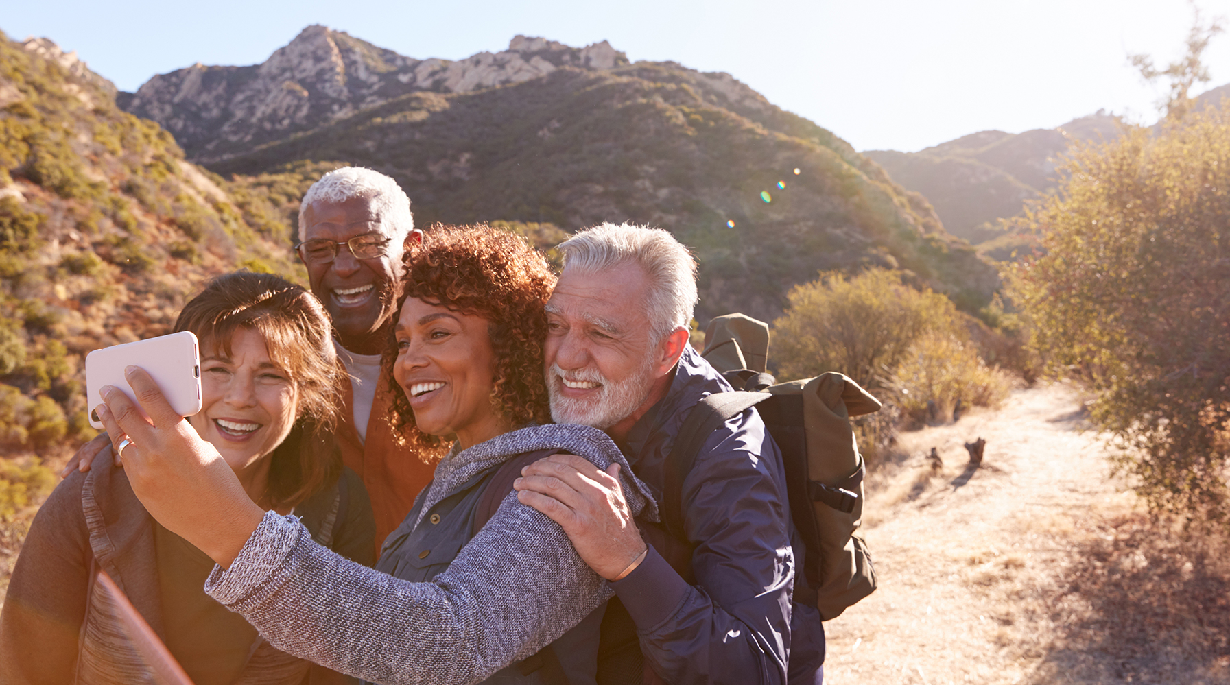 Group Of Senior Friends Posing For Selfie As They Hike Along Trail In Countryside Together.